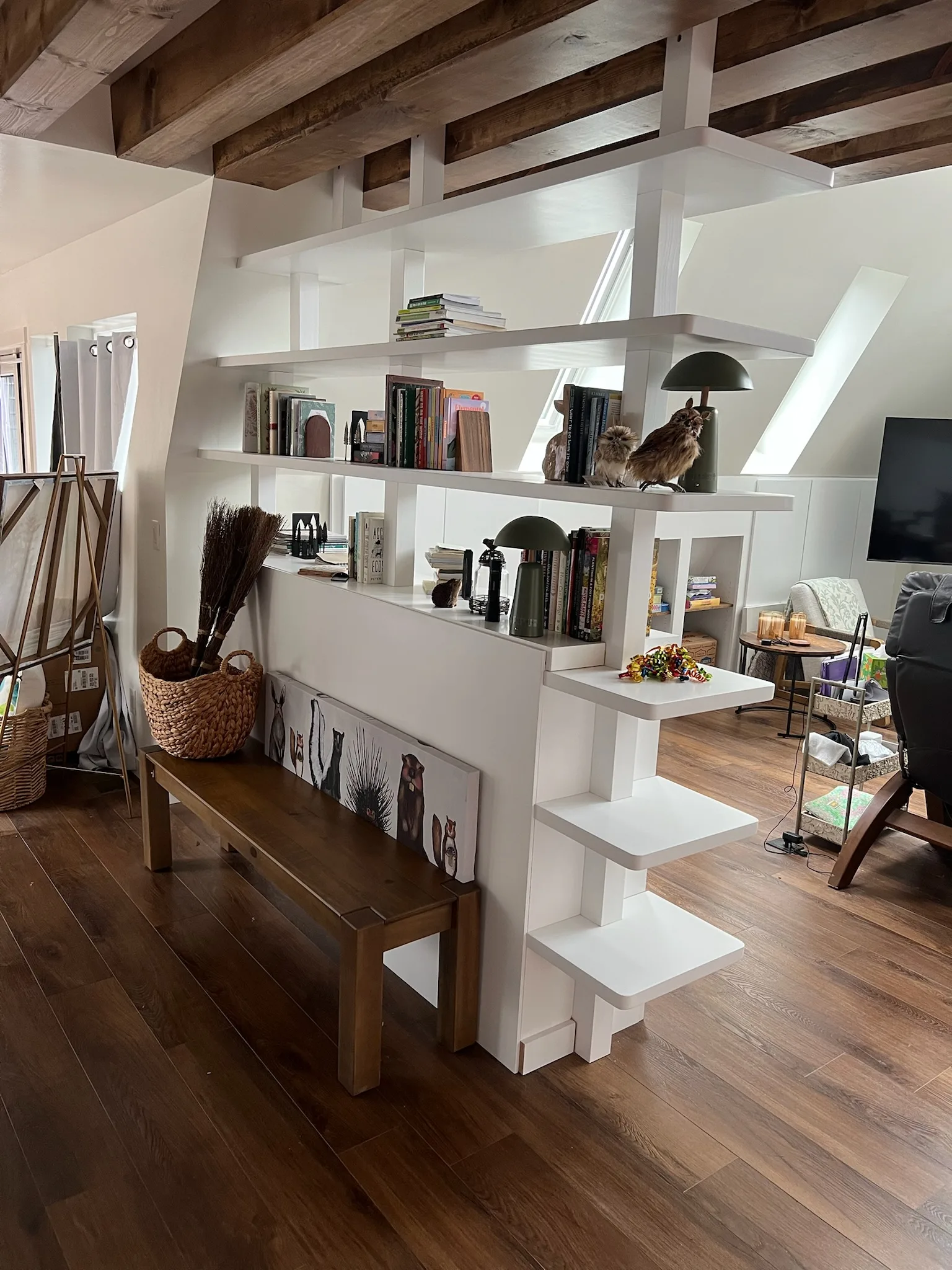 Back view of white bookshelf room divider with bench and exposed beams by Sims Custom Woodwork.
