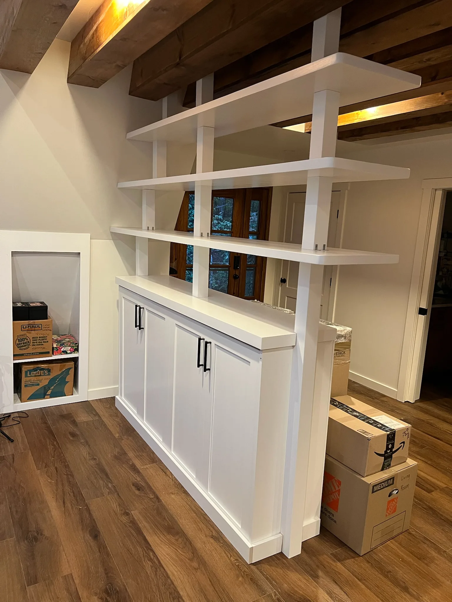 Cabinet base detail of white bookshelf room divider with matte black hardware by Sims Custom Woodwork.