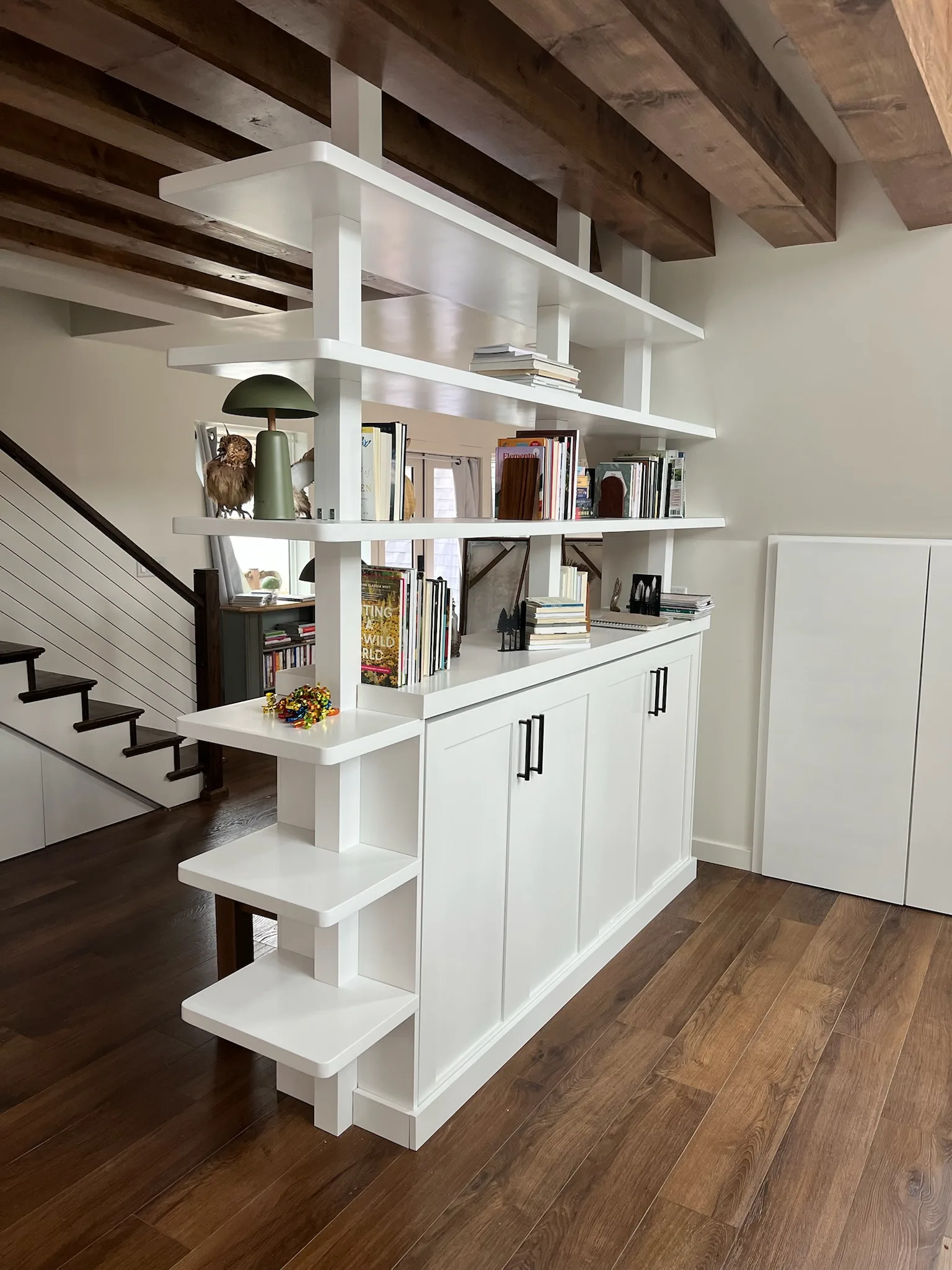 Bookshelf room divider near staircase with cable railing by Sims Custom Woodwork.