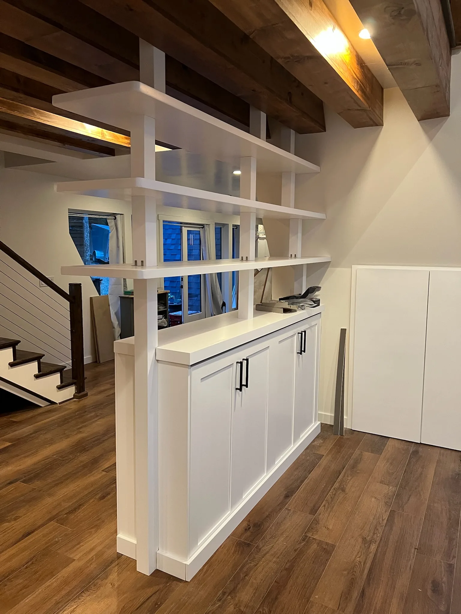Bookshelf room divider seen from staircase with cable railing by Sims Custom Woodwork.