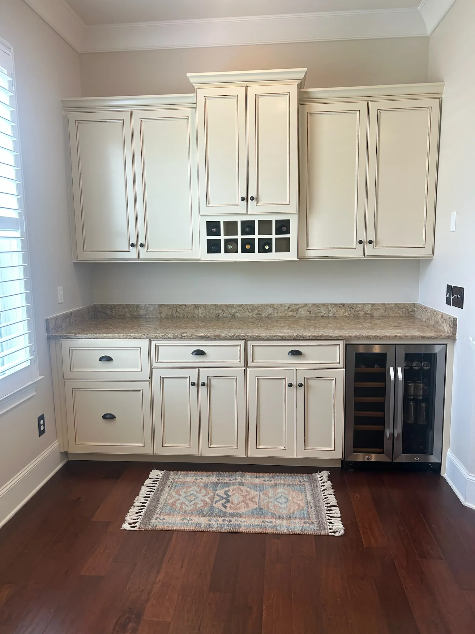 Cream raised-panel butler pantry with wine rack and granite counter by Sims Custom Woodwork.