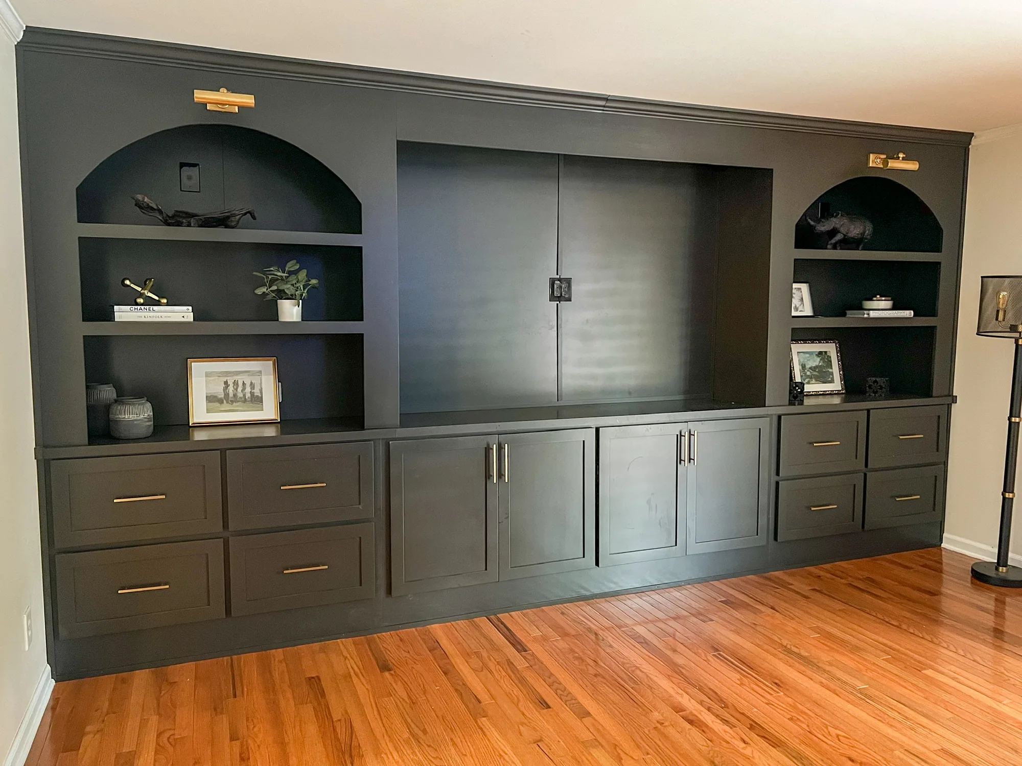Angled view of dark entertainment center with styled arched niches by Sims Custom Woodwork.