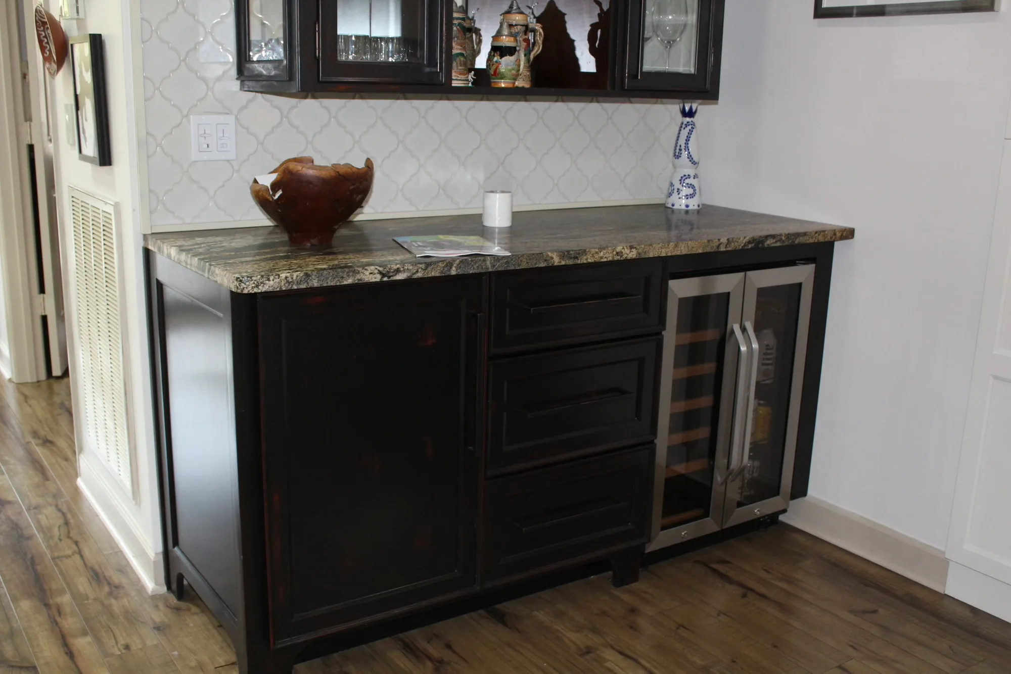 Dark espresso wet bar with wine cooler and glass-front uppers by Sims Custom Woodwork.