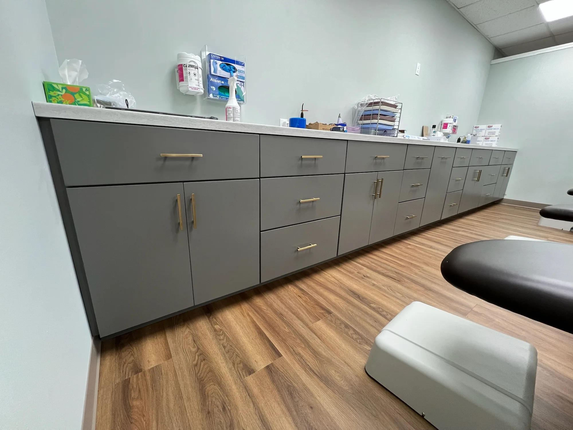 Dental office cabinet run with gray flat-panel doors and gold pulls by Sims Custom Woodwork.