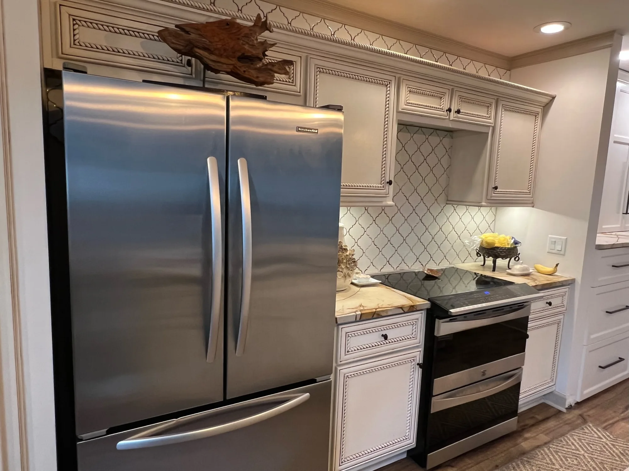 Custom built-in refrigerator surround with decorative rope-detail cabinetry by Sims Custom Woodwork.