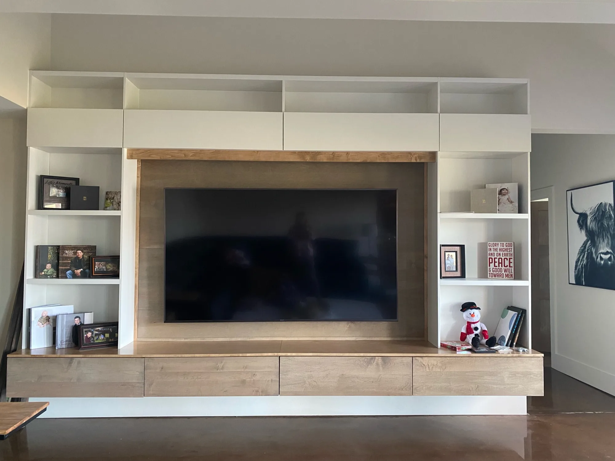 Front view of floor-to-ceiling entertainment center with wood accents by Sims Custom Woodwork.