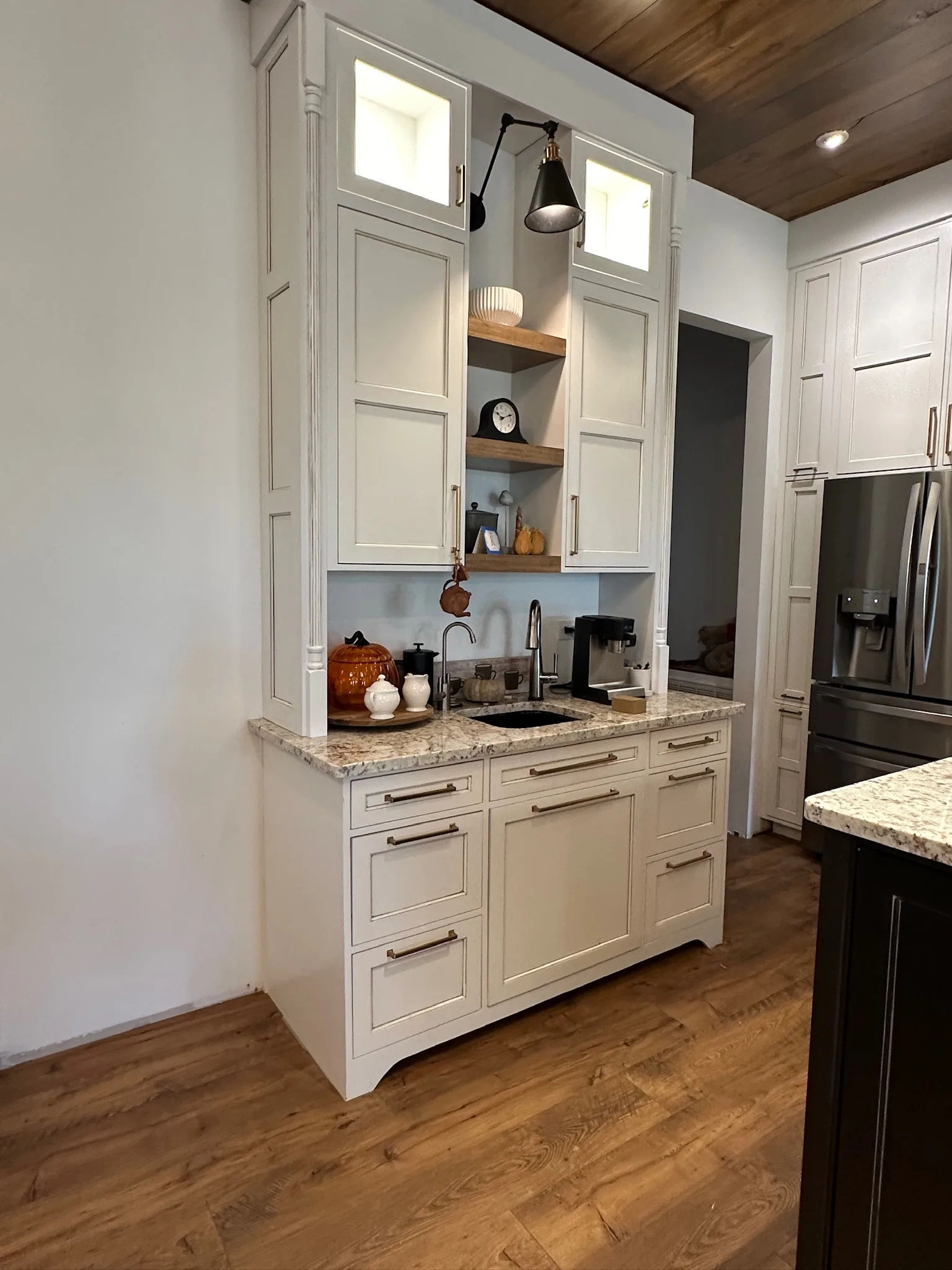 Farmhouse kitchen beverage niche with white cabinets and floating shelves by Sims Custom Woodwork.