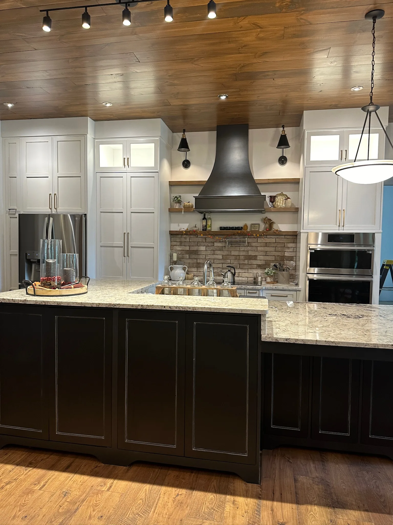 Farmhouse kitchen range wall with metal hood and brick backsplash by Sims Custom Woodwork.