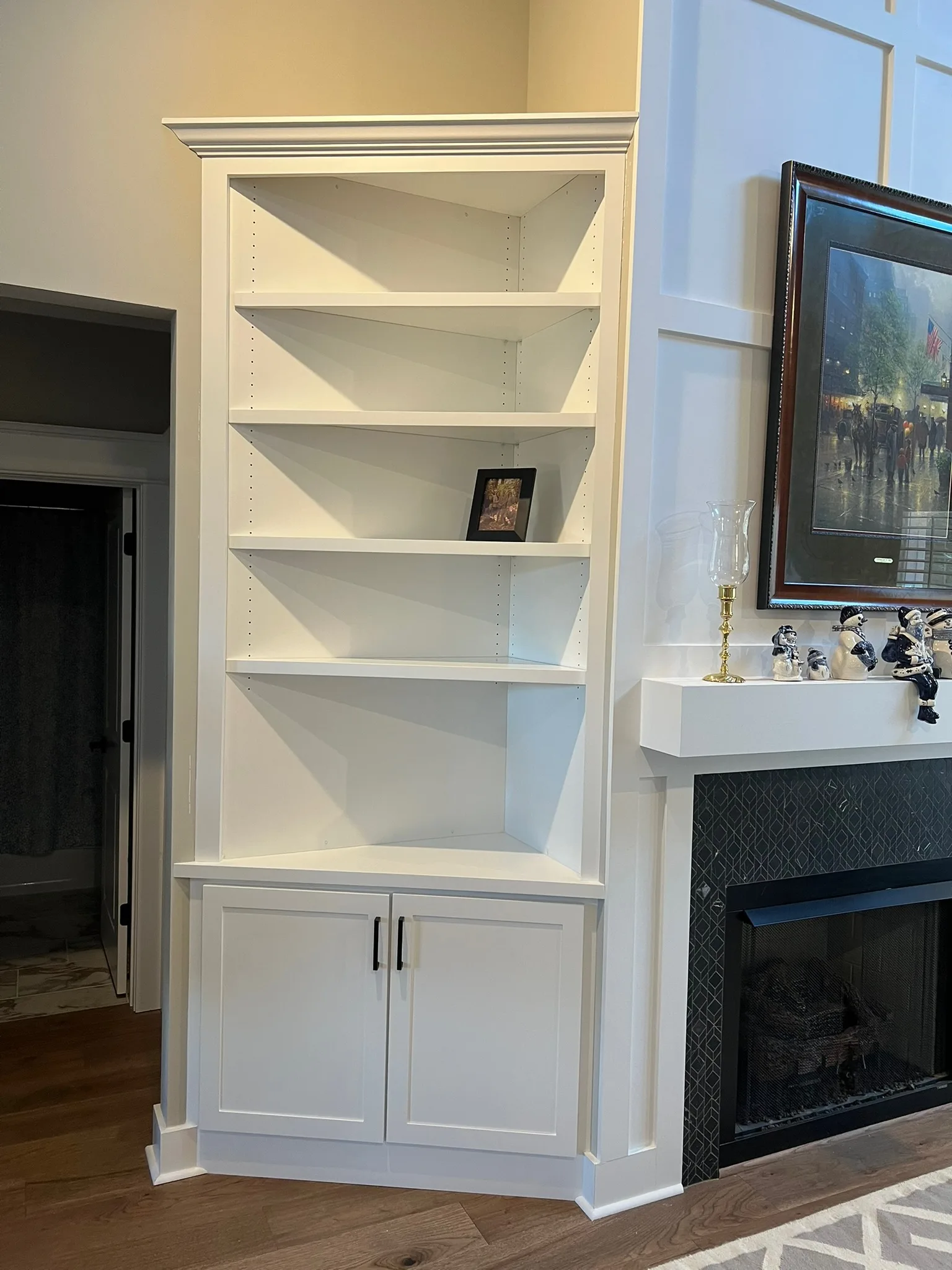Built-in corner bookshelf with lower cabinets beside fireplace by Sims Custom Woodwork.
