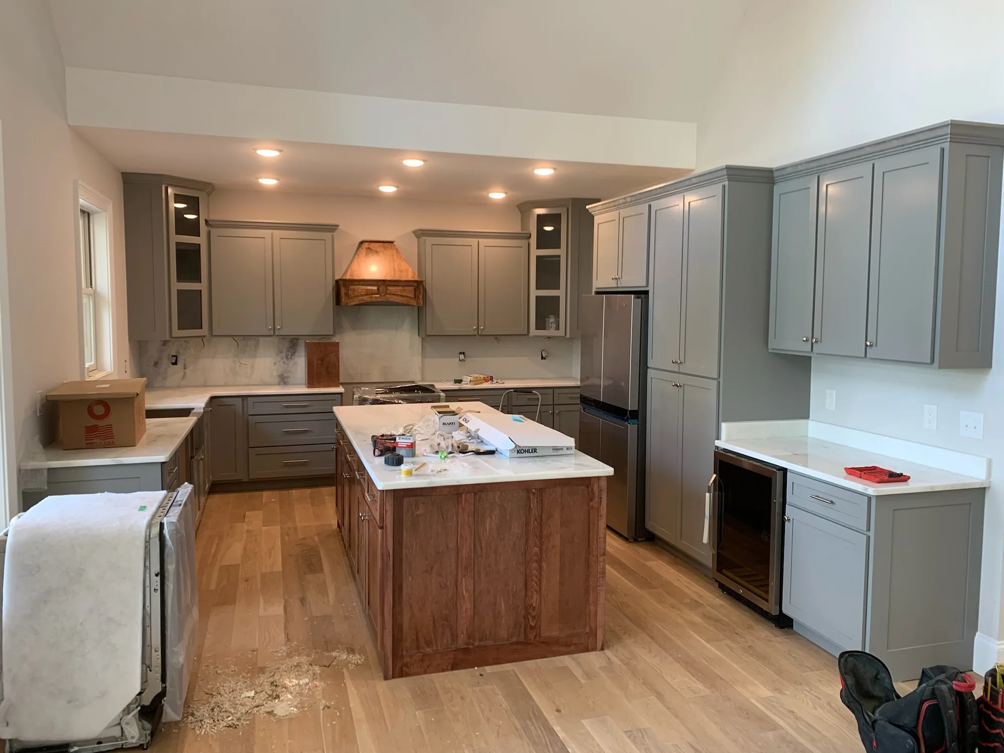 Gray shaker kitchen with stained wood island and copper range hood by Sims Custom Woodwork.