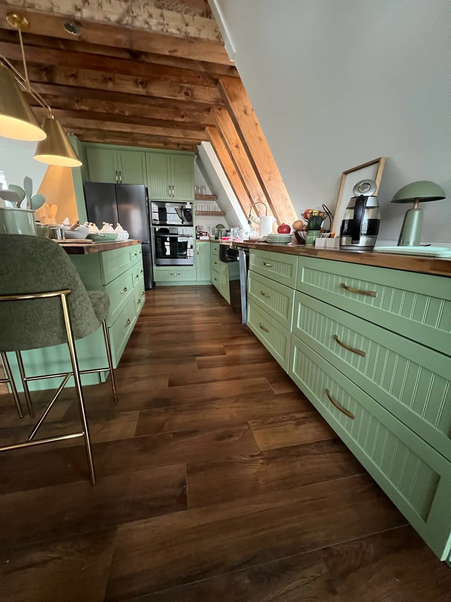 Sage green beadboard kitchen with exposed wood beam vaulted ceiling by Sims Custom Woodwork.