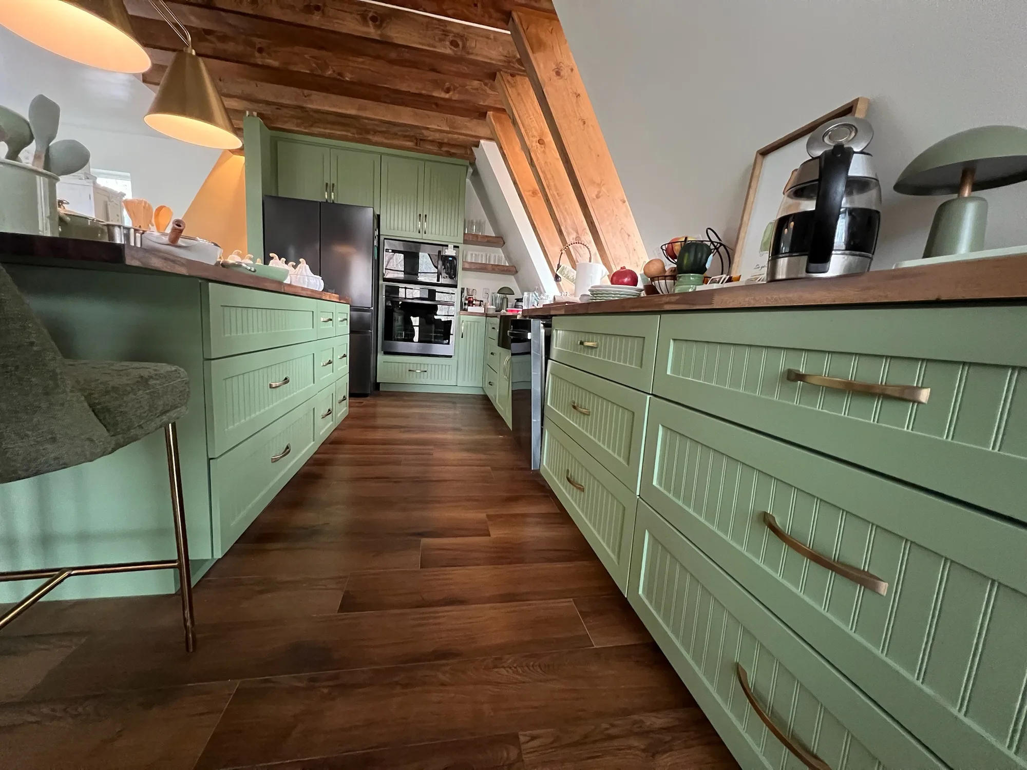 Wide galley view of sage green beadboard kitchen with walnut counters and exposed beams by Sims Custom Woodwork — Chattanooga area custom kitchen cabinetry.