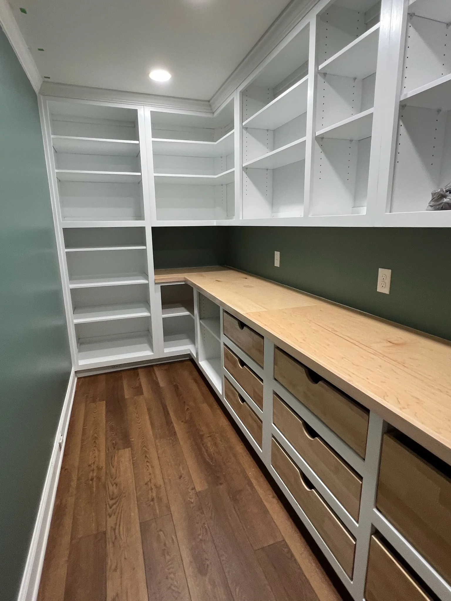 Walk-in pantry corner with open shelving and wood drawer counter by Sims Custom Woodwork.