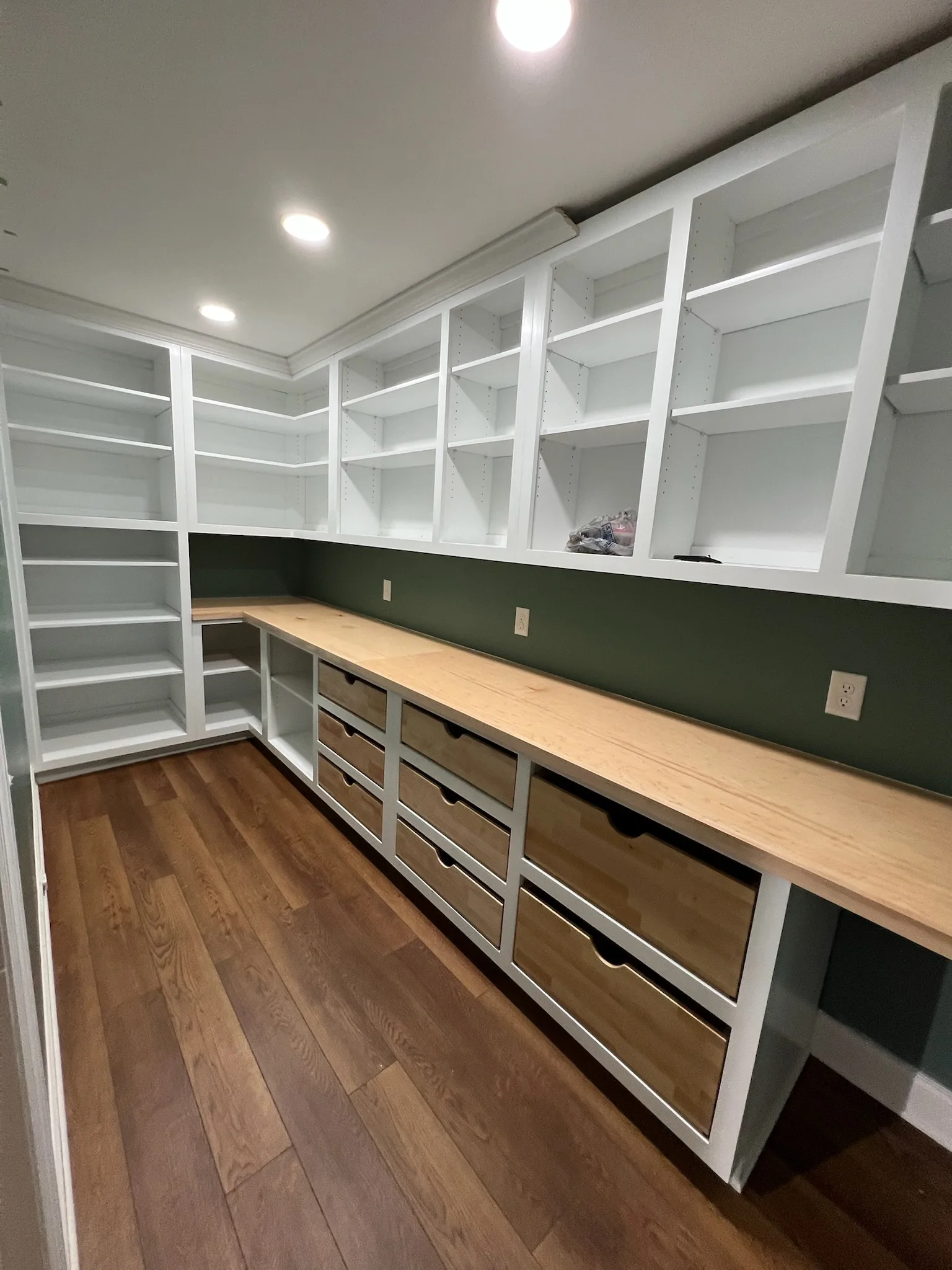 Full layout view of L-shaped green pantry with wood drawers and butcher block counter by Sims Custom Woodwork — custom pantry cabinetry serving Chattanooga and North Georgia.