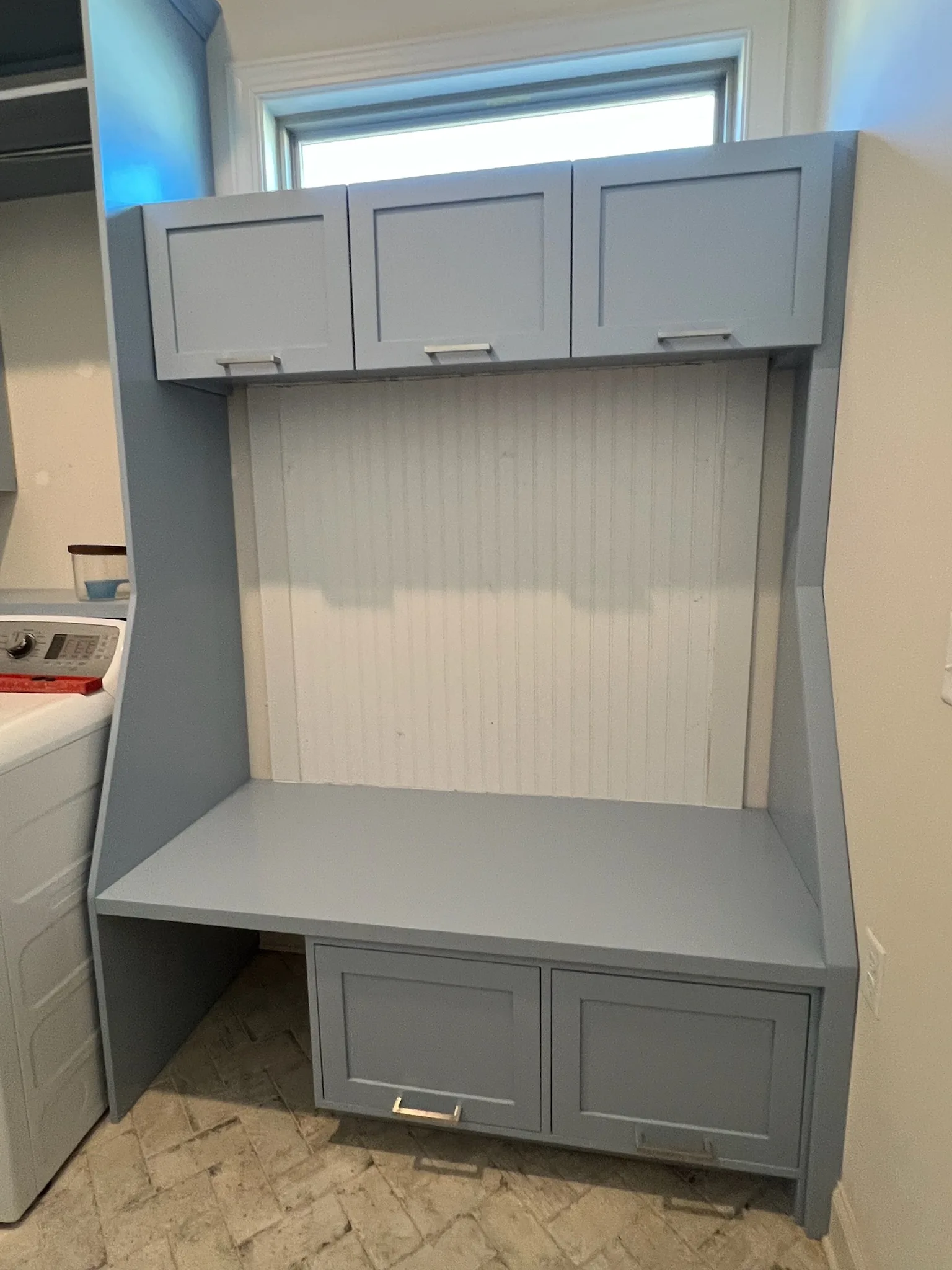 Built-in laundry folding station with beadboard panel and cubby cabinets by Sims Custom Woodwork.
