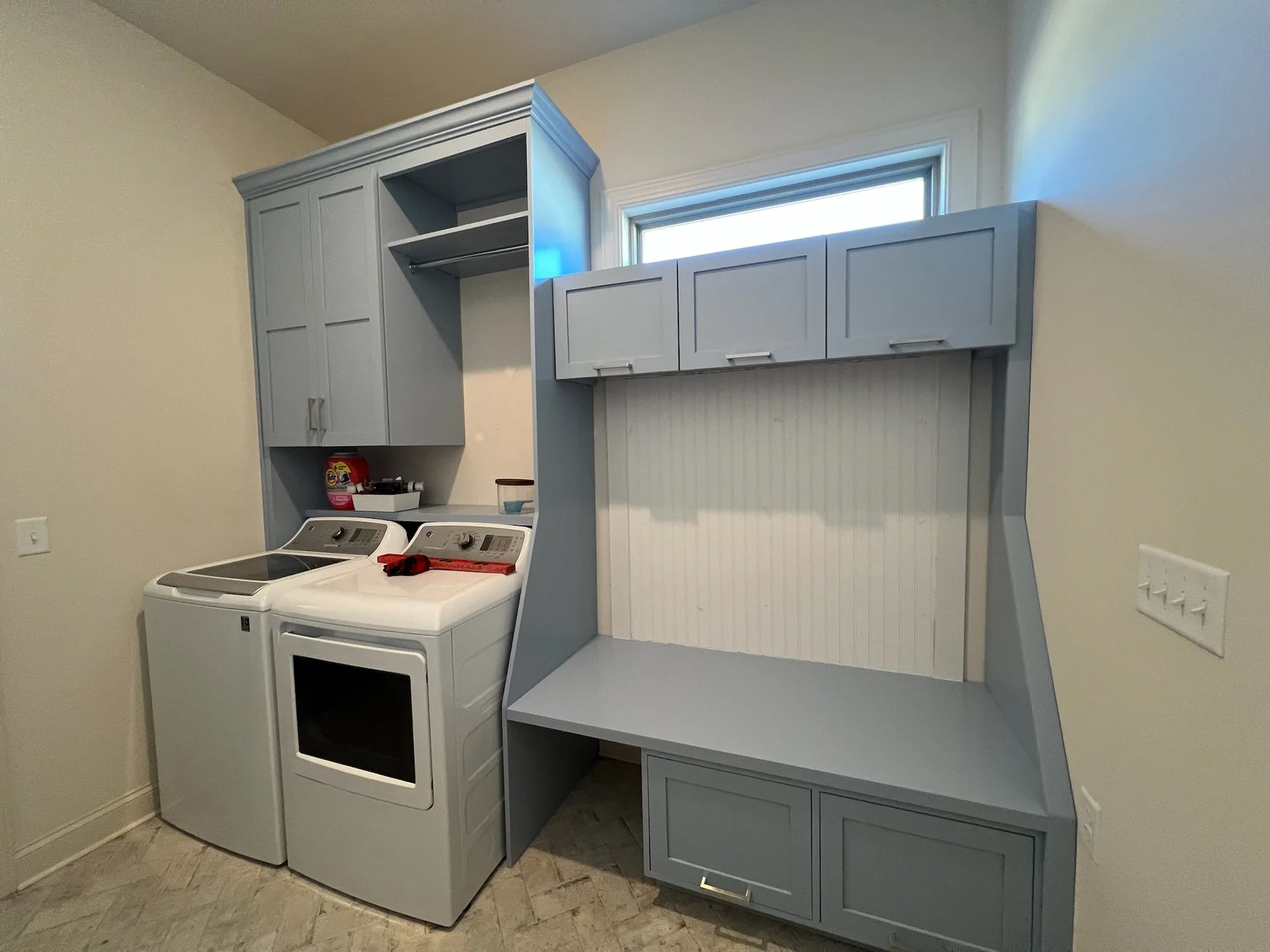 Full custom laundry room with blue-grey cabinetry, washer surround, and folding station by Sims Custom Woodwork.