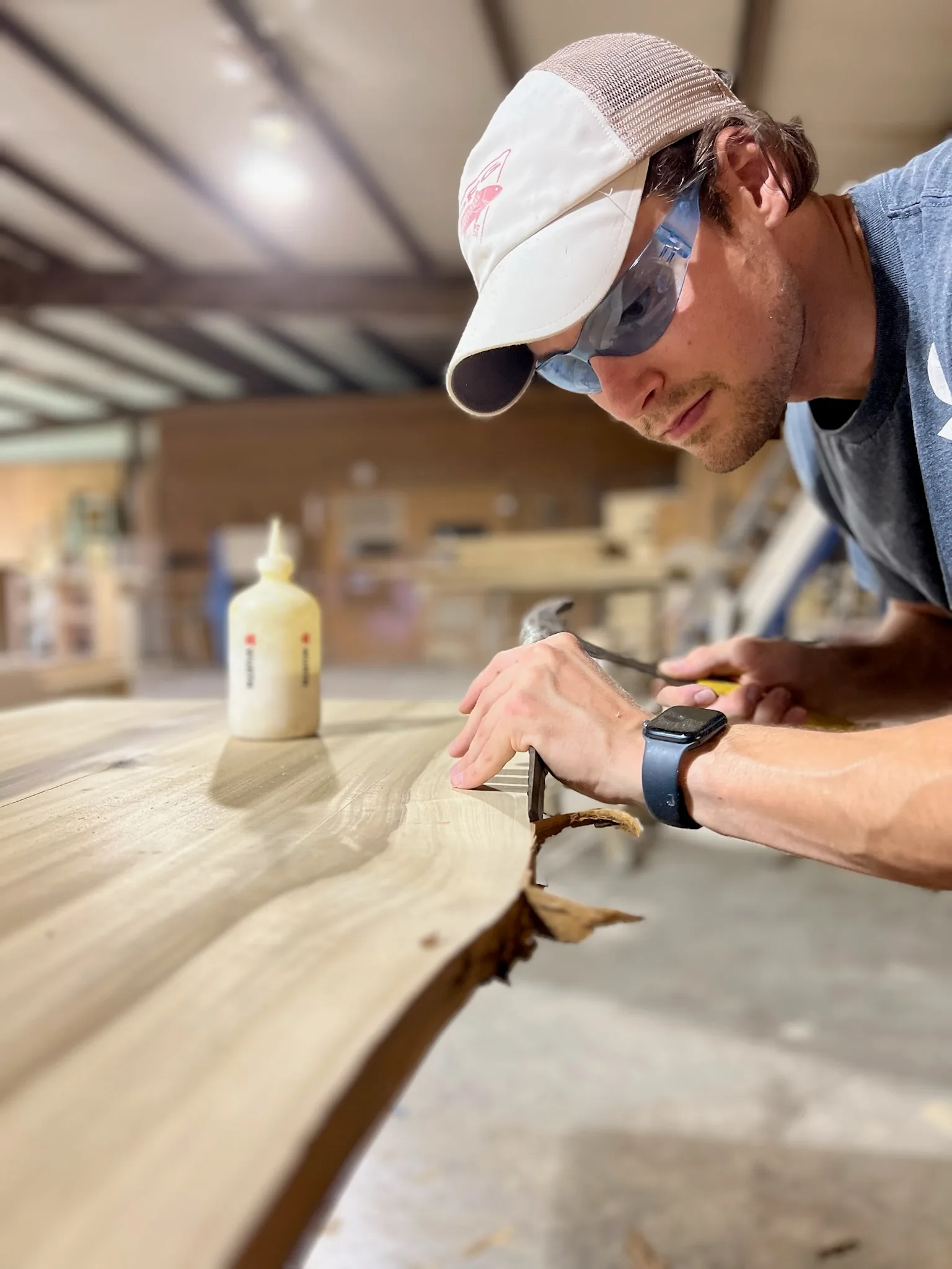 Portrait of Sims Custom Woodwork craftsman debarking a live-edge slab with a chisel.