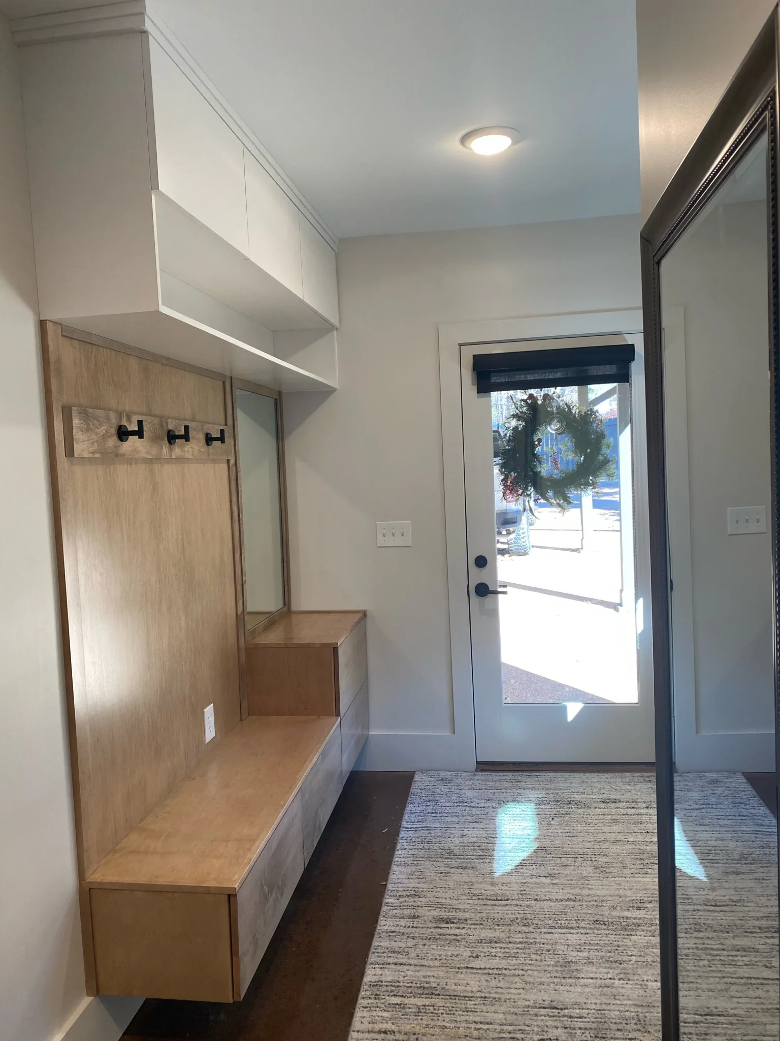 Full mudroom entryway with built-in bench and upper cabinets by Sims Custom Woodwork.