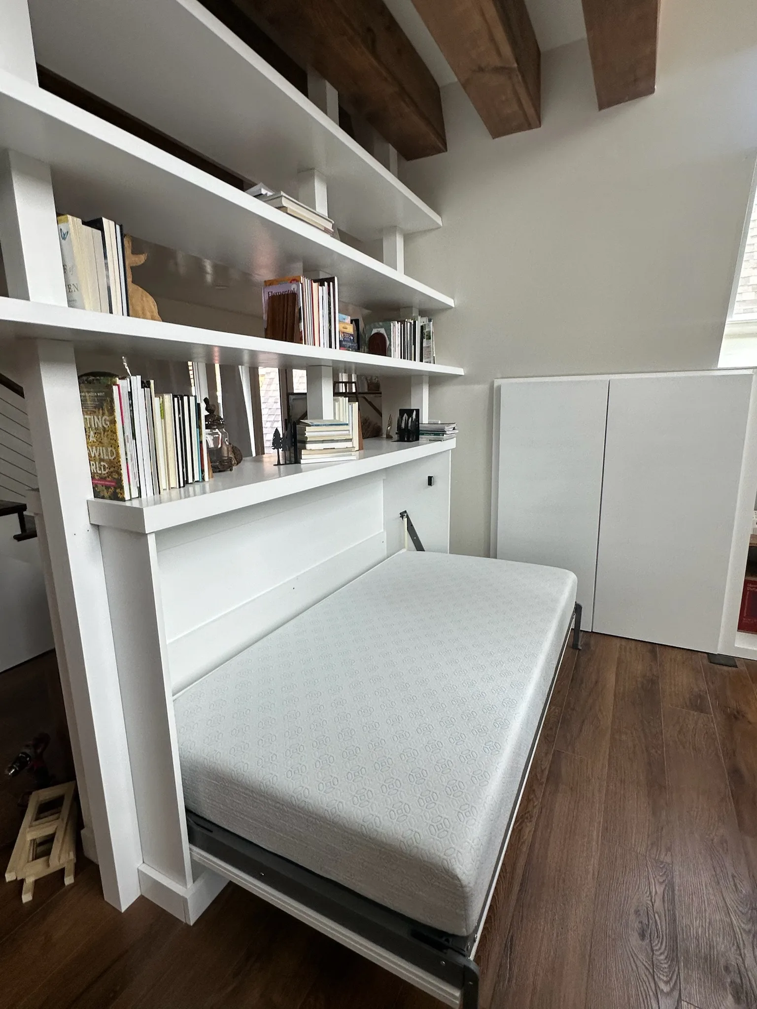 Murphy bed folded down from built-in bookshelf unit by Sims Custom Woodwork.