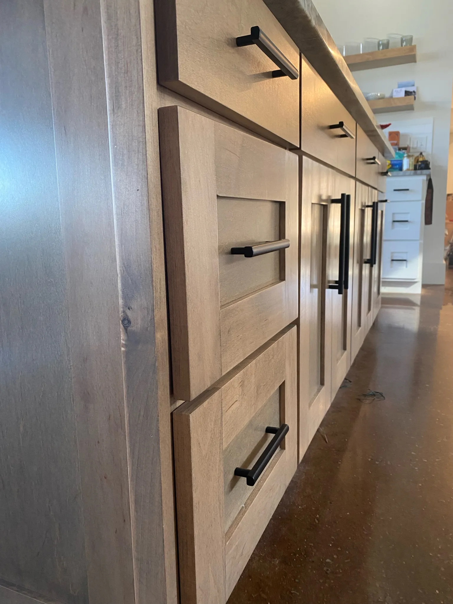 Natural stained wood island cabinetry with matte black hardware by Sims Custom Woodwork.