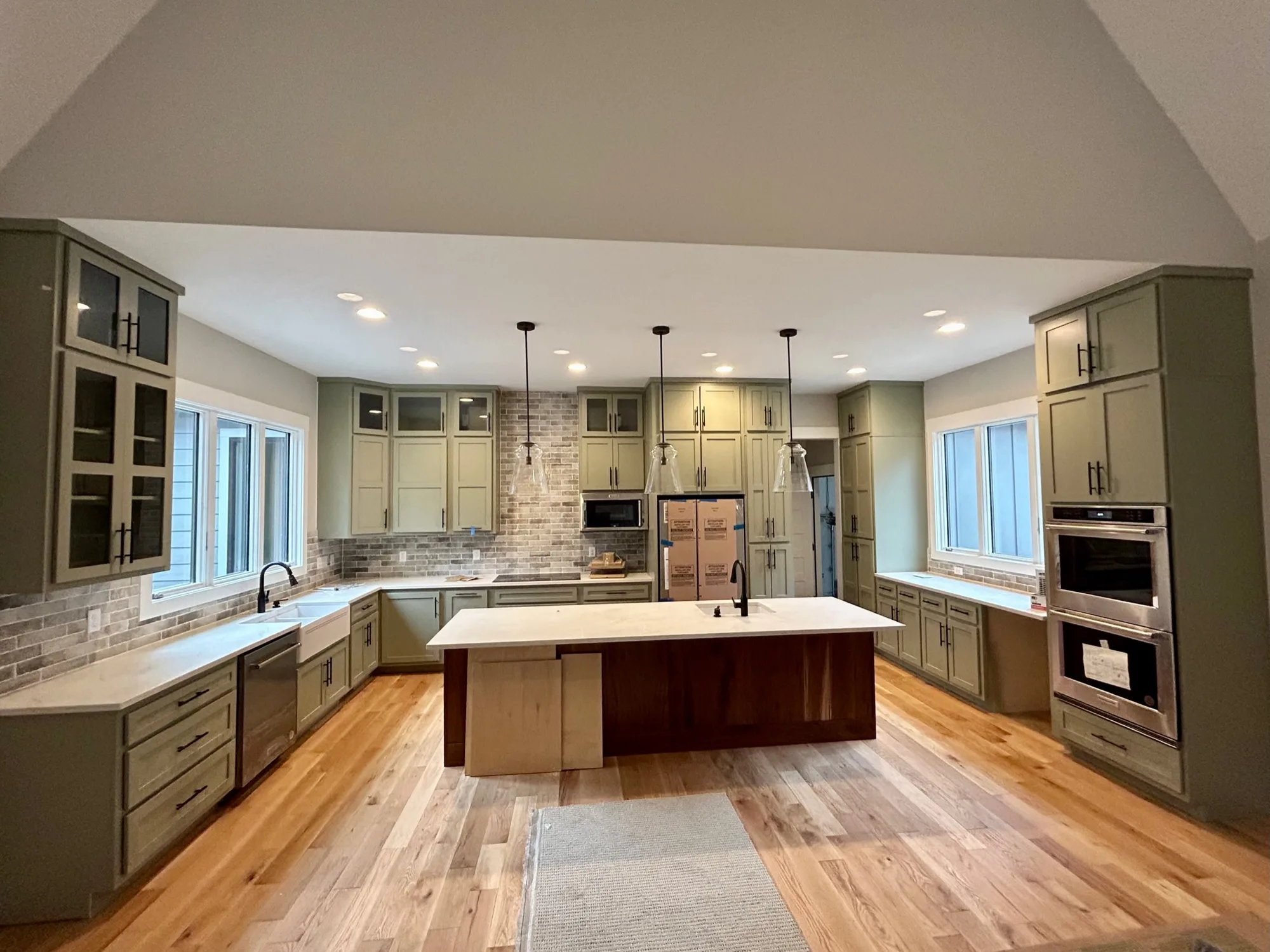 Olive green shaker kitchen with walnut island and brick backsplash by Sims Custom Woodwork.