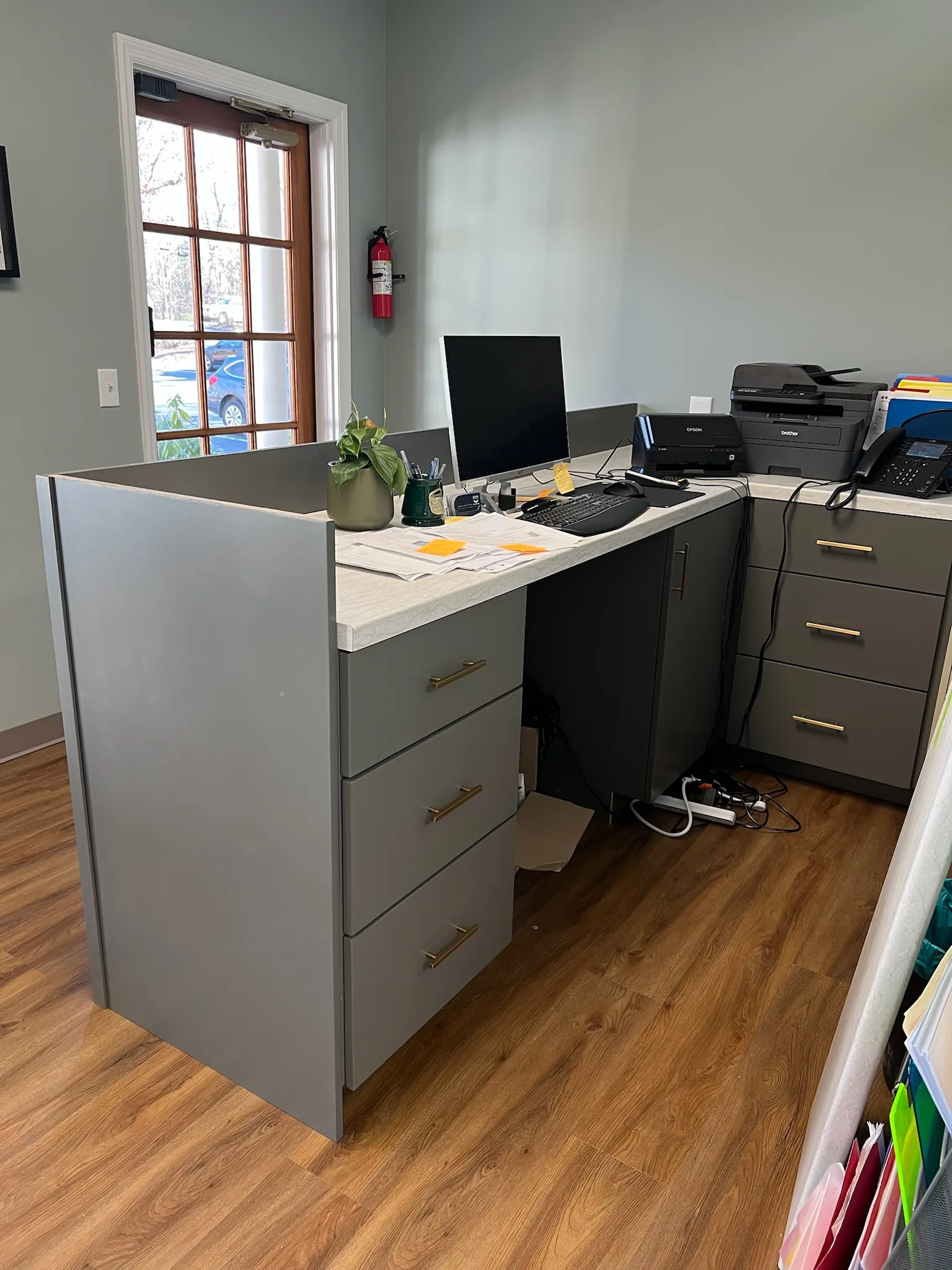 Custom commercial reception desk with gray flat-panel construction and gold hardware by Sims Custom Woodwork — North Georgia and Chattanooga commercial cabinetry.