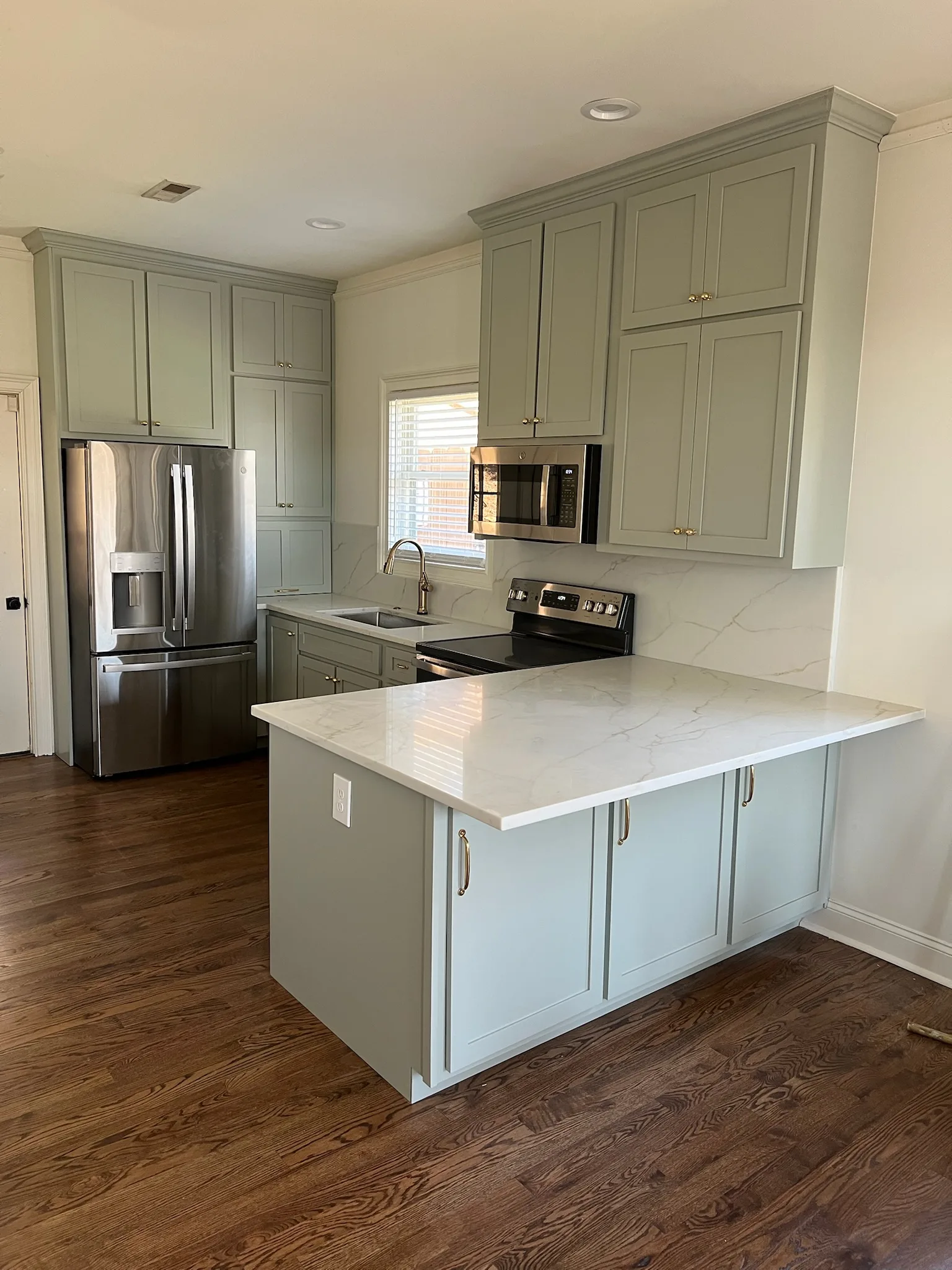Sage green kitchen island with quartz countertop from alternate angle by Sims Custom Woodwork.