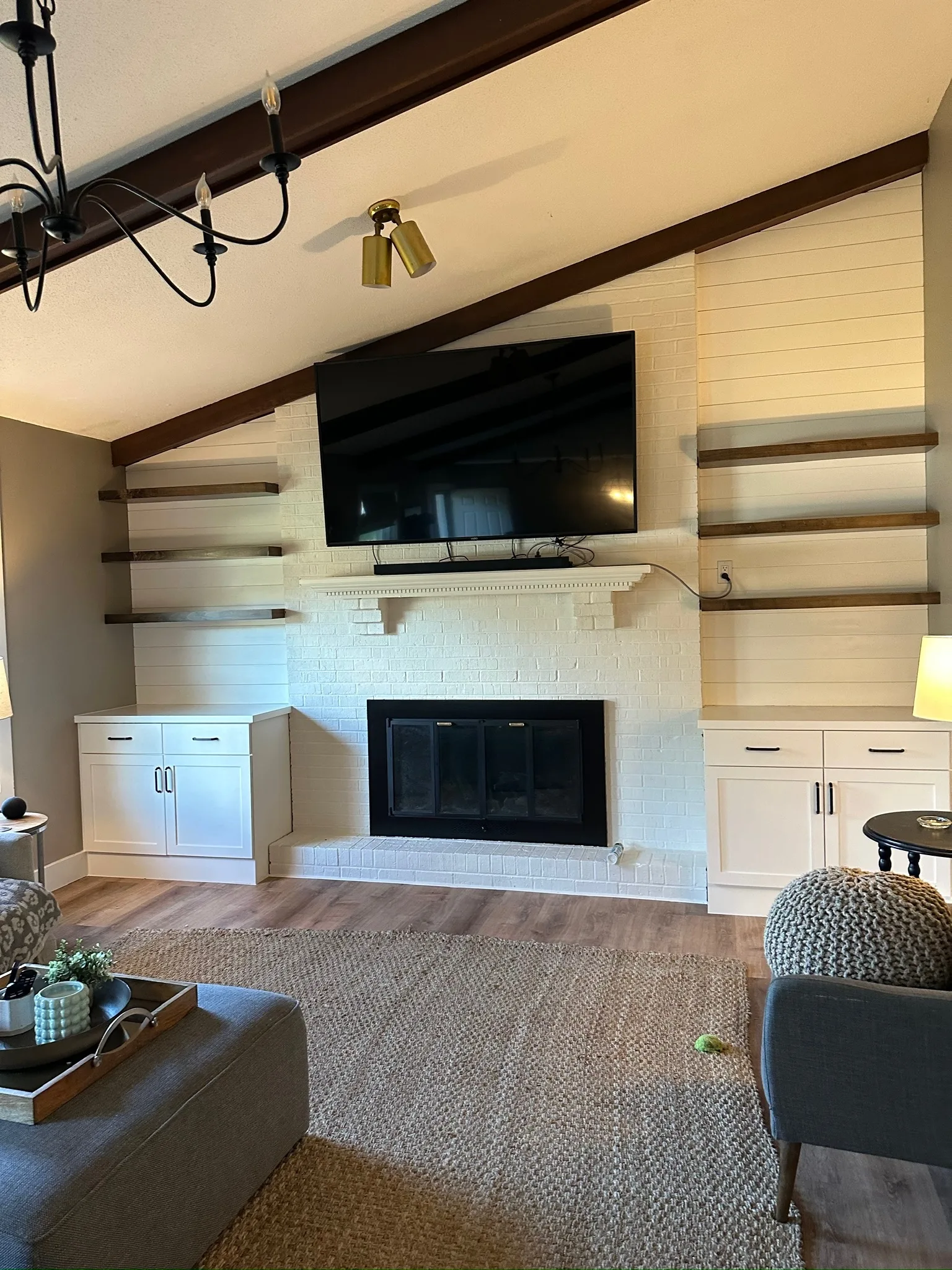 Shiplap fireplace wall with walnut floating shelves and white base cabinets by Sims Custom Woodwork.
