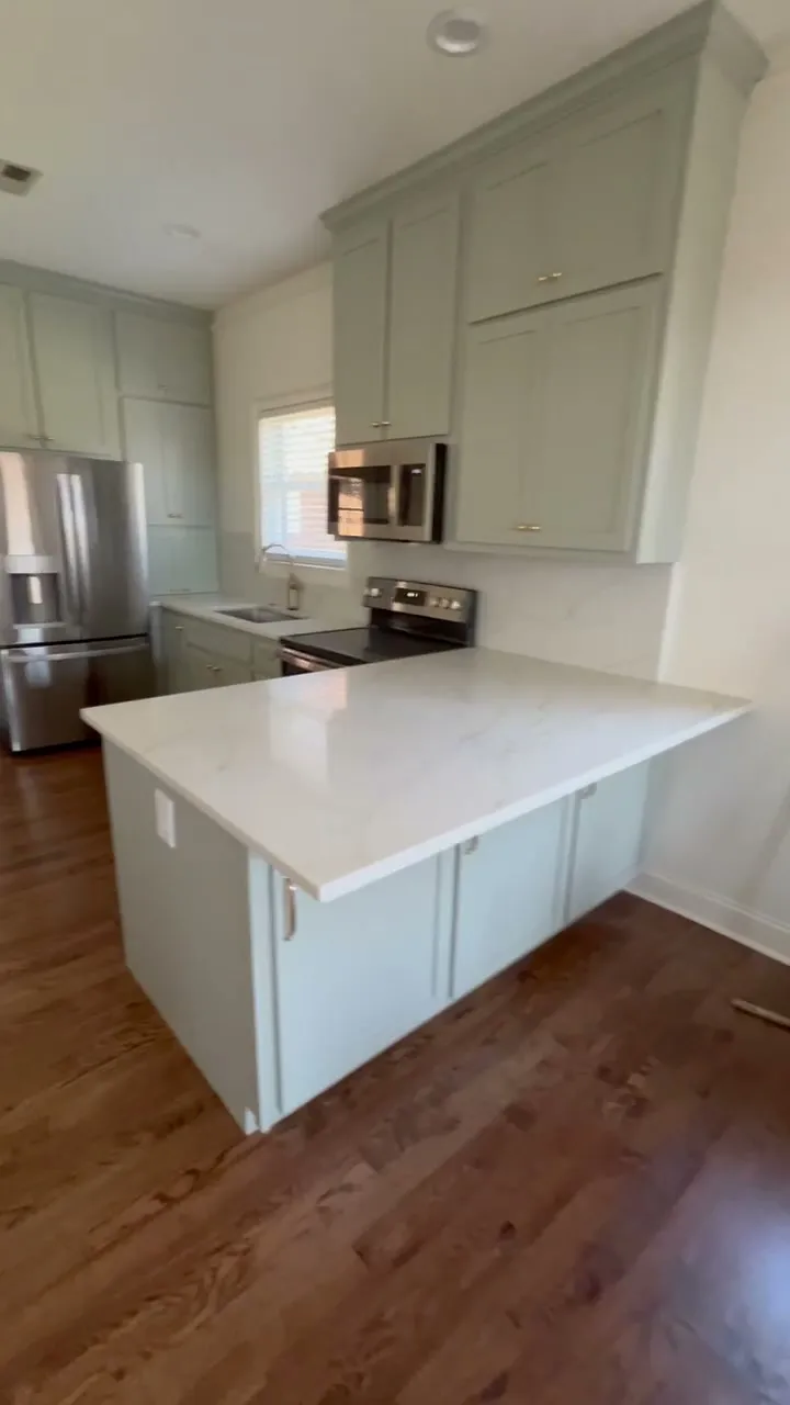 Video reveal of sage green shaker kitchen with quartz island and brass hardware by Sims Custom Woodwork.