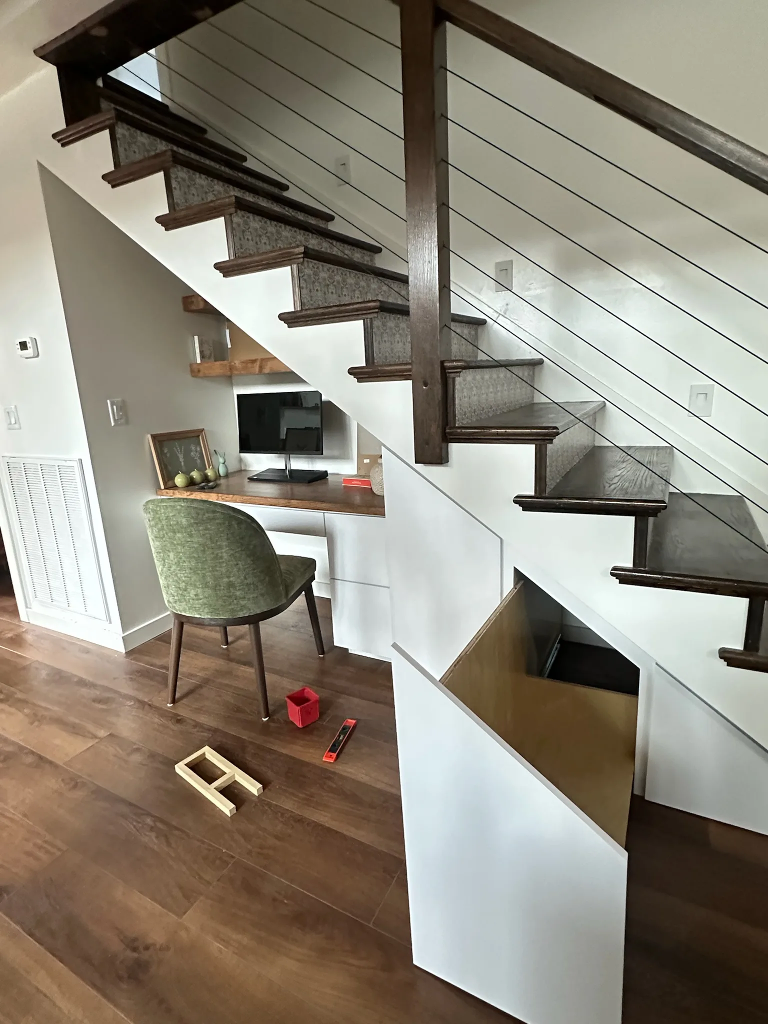 Built-in desk with hidden storage under modern staircase by Sims Custom Woodwork.