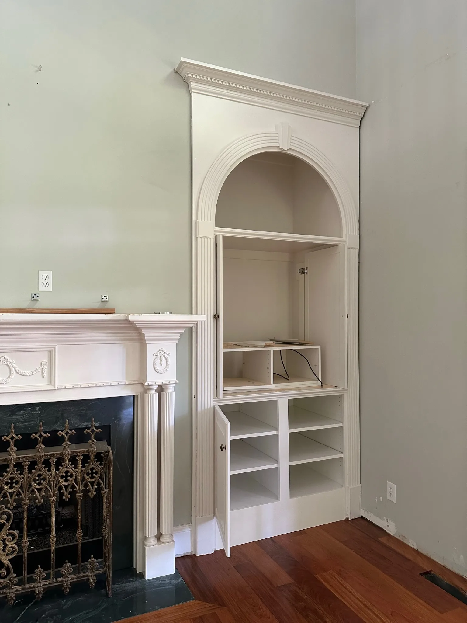 Victorian arched built-in niche with crown molding beside ornate fireplace by Sims Custom Woodwork.