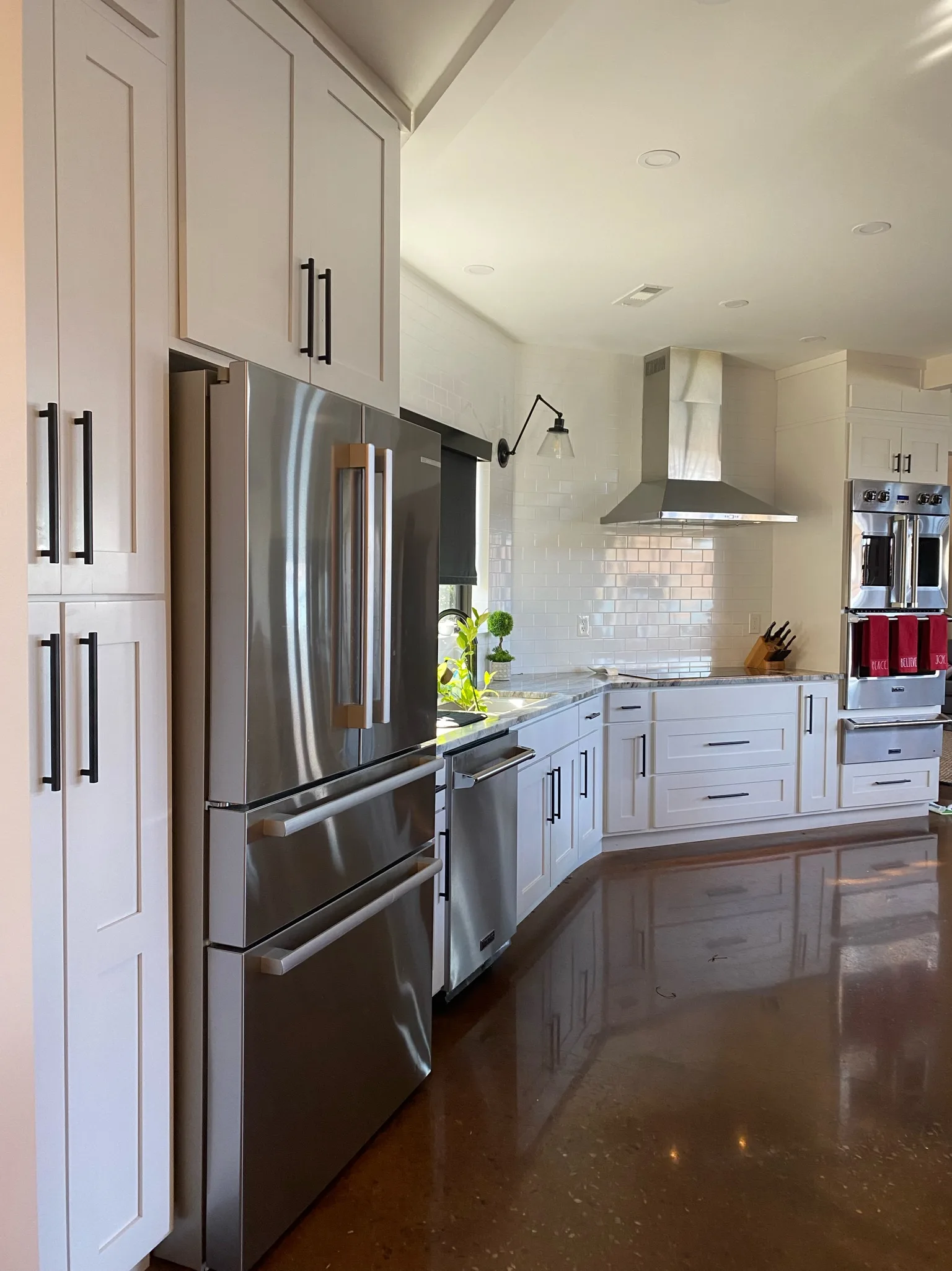 White shaker kitchen with tall pantry cabinets and stainless refrigerator by Sims Custom Woodwork.