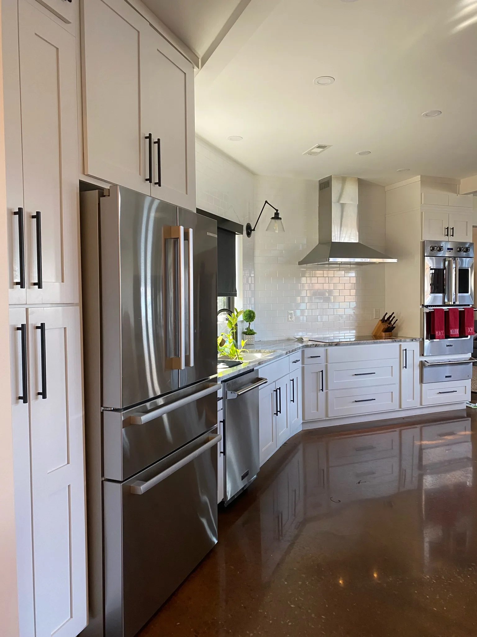 White shaker kitchen perimeter cabinetry with range hood and double oven by Sims Custom Woodwork.
