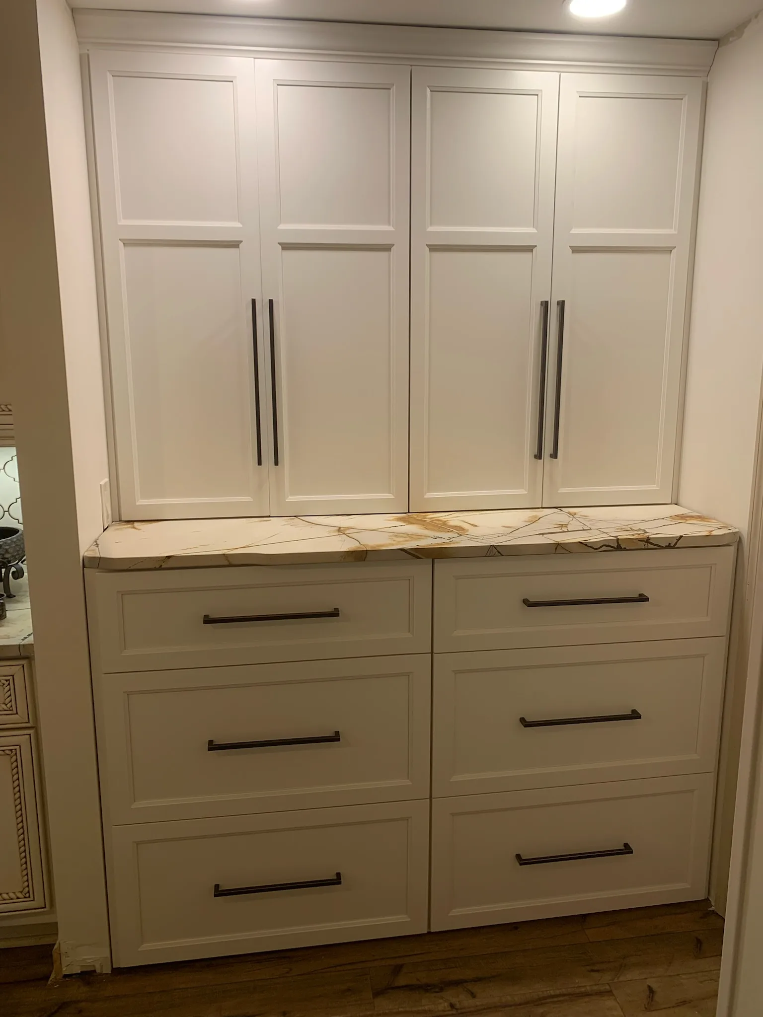White shaker pantry with marble countertop and matte black pulls by Sims Custom Woodwork.